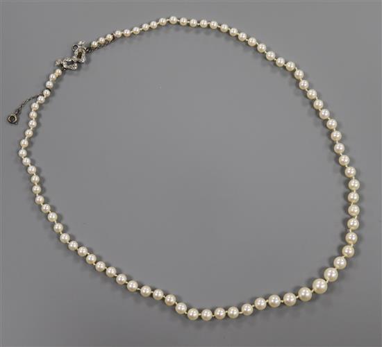 A 1920s/1930s single strand graduated cultured pearl necklace with white metal and diamond set bow clasp, 50cm.